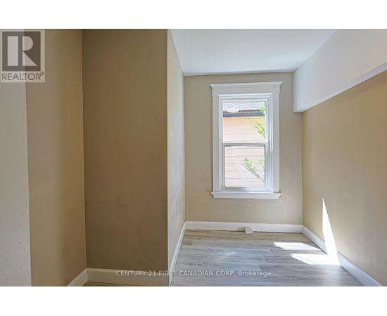 A room with a window showing a view of a house and trees outside.