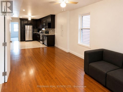 A living room with a black couch and wooden floors.