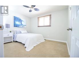 A bedroom with a bed, nightstand, and a painting of a wave on the wall.