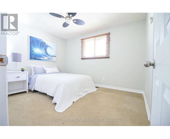 A bedroom with a bed, nightstand, and a painting of a wave on the wall.