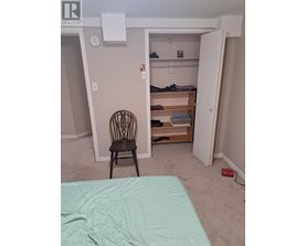 A chair sits in a bedroom with a bed and a closet.