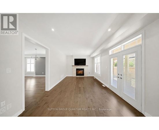 A spacious living room with a fireplace and wooden floors.