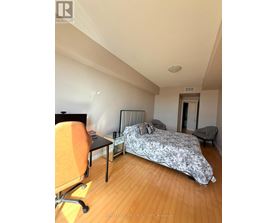 A bedroom with a bed, chair, and desk.