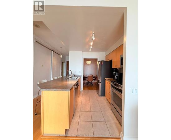 A kitchen with a refrigerator, sink, and cabinets.