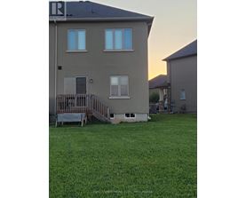 A house with a deck and a green lawn in front.