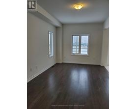A room with wood flooring and two windows.