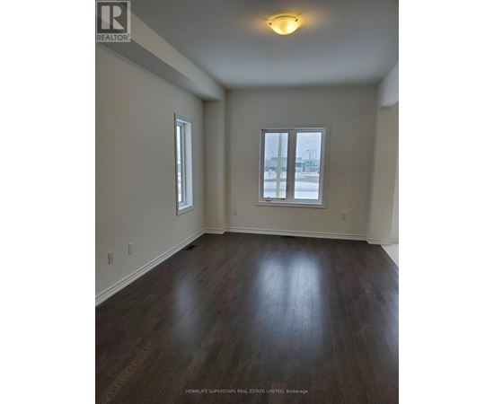 A room with wood flooring and two windows.