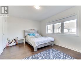 A bedroom with a bed, a teddy bear, a nightstand, a rug, and a window.