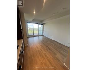 A spacious room with wooden flooring and a large window.