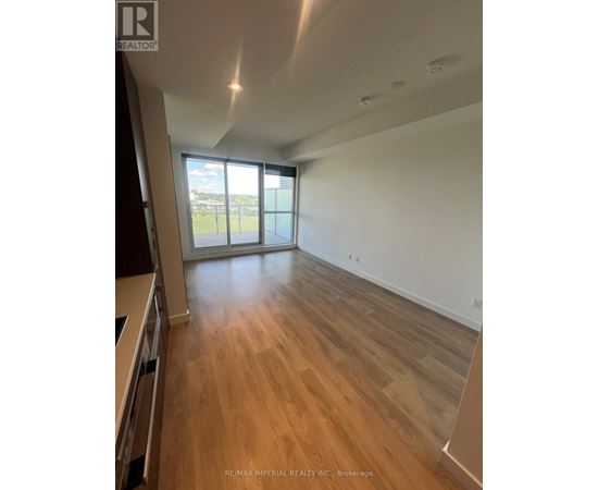 A spacious room with wooden flooring and a large window.