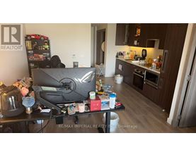 A cluttered kitchen and living room with a TV and vending machine.