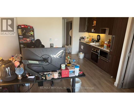 A cluttered kitchen and living room with a TV and vending machine.