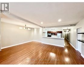 A spacious room with wooden flooring and white walls.