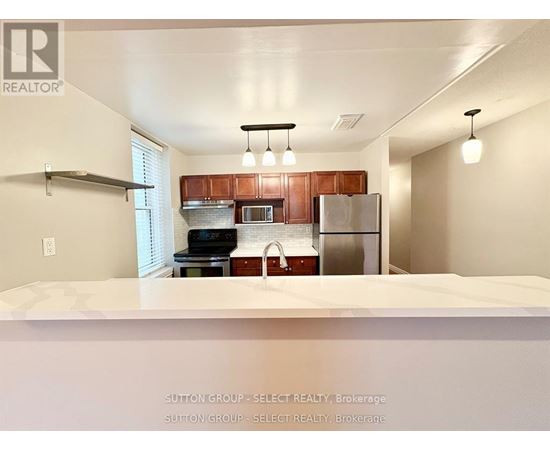 A kitchen with a refrigerator, microwave, and oven.