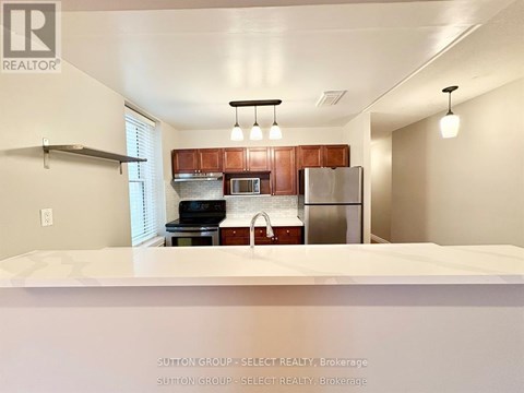 A kitchen with a refrigerator, microwave, and oven.