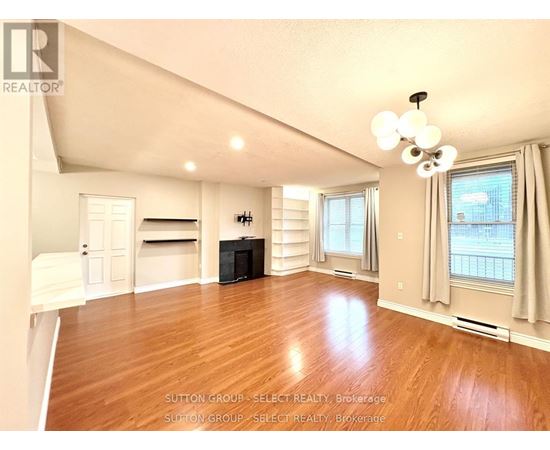 A spacious living room with hardwood floors and a flat-screen TV.
