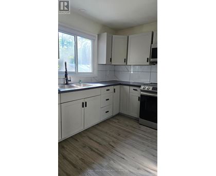 A kitchen with white cabinets and a wooden floor.
