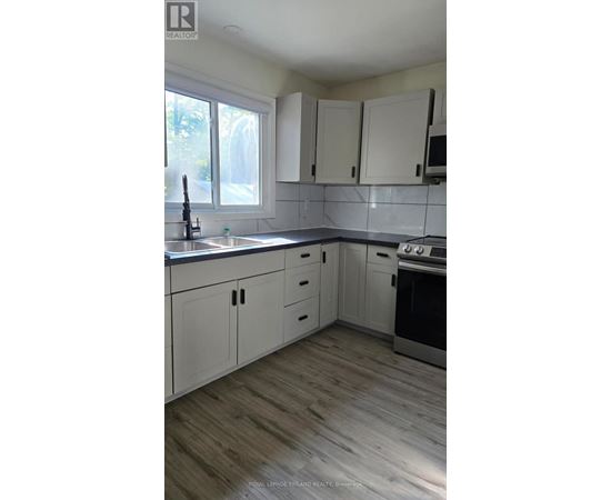 A kitchen with white cabinets and a wooden floor.