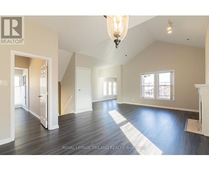 A large, empty room with wooden floors and a chandelier hanging from the ceiling.