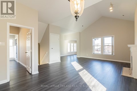 A large, empty room with wooden floors and a chandelier hanging from the ceiling.