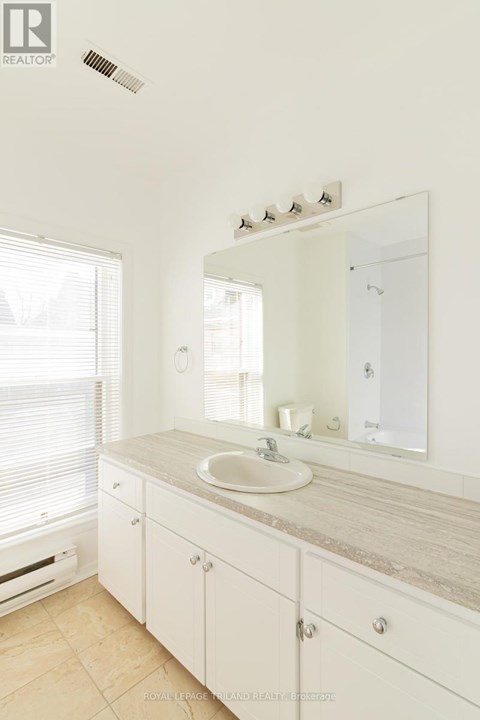 A bathroom with a sink, mirror, and cabinet.
