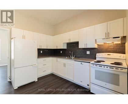 A white refrigerator is in a kitchen with white cabinets.