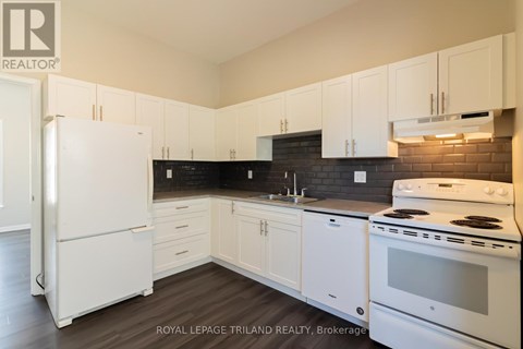 A white refrigerator is in a kitchen with white cabinets.