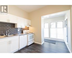 A kitchen with white cabinets and a black tile backsplash.