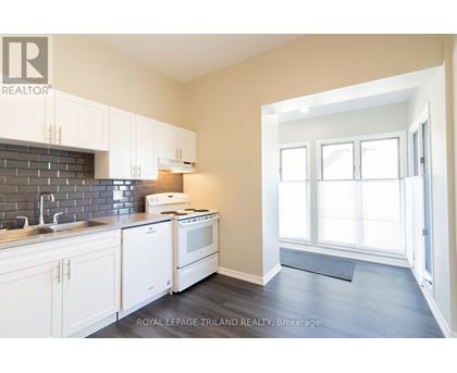 A kitchen with white cabinets and a black tile backsplash.