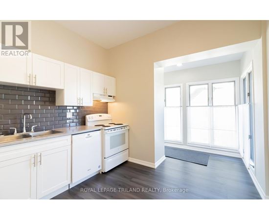 A kitchen with white cabinets and a black tile backsplash.