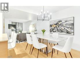 A modern dining room with a glass table and white chairs.