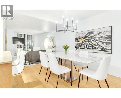 A modern dining room with a glass table and white chairs.