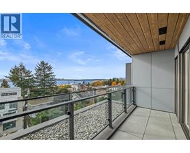 A balcony with a glass railing and a view of a lake and trees.