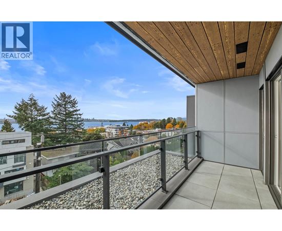 A balcony with a glass railing and a view of a lake and trees.