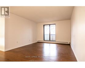 A white room with a window and wooden flooring.