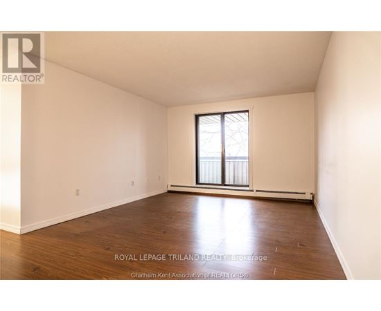 A white room with a window and wooden flooring.