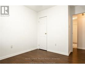 A white door is in the middle of a room with wood flooring.