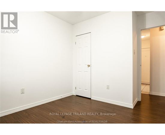A white door is in the middle of a room with wood flooring.