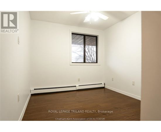 A white room with a window and a ceiling fan.