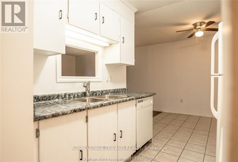 A kitchen with white cabinets and a marble countertop.