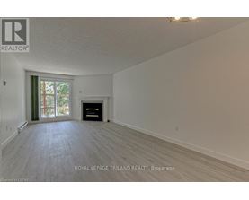 A spacious room with a fireplace and a window with curtains.