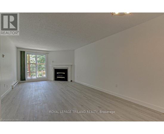 A spacious room with a fireplace and a window with curtains.
