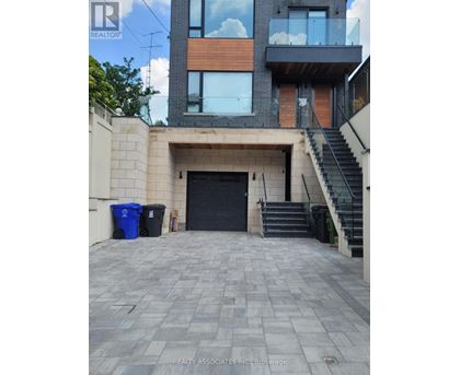 A modern house with a black door and a staircase leading to the second floor.