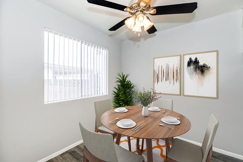 A dining room with a table set for two and a ceiling fan.