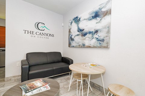 A living room with a couch, a coffee table, and a painting on the wall.