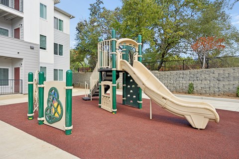 A playground with a green and yellow slide and a tan slide.