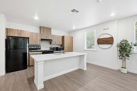 A modern kitchen with a black refrigerator and wooden cabinets.