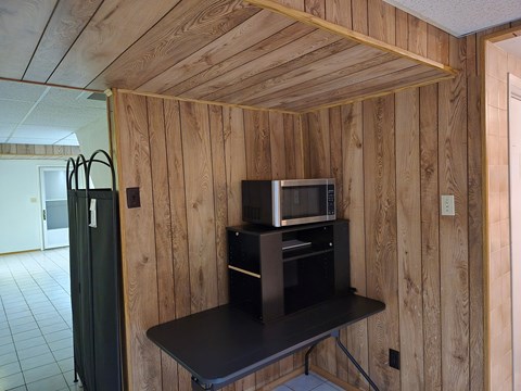 A microwave and oven are on a shelf in a kitchen.