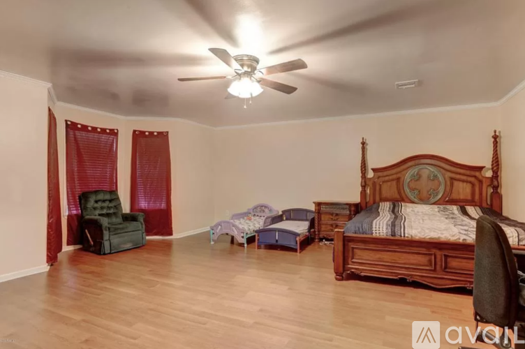 A bedroom with a large bed, a chair, and a small bed in the corner.
