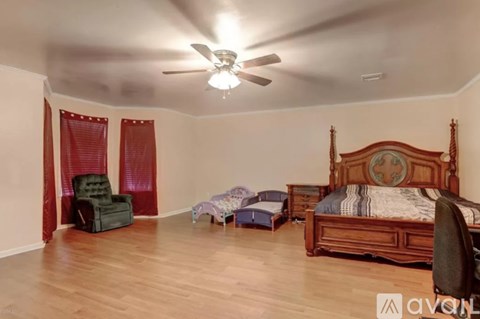 A bedroom with a large bed, a chair, and a small bed in the corner.